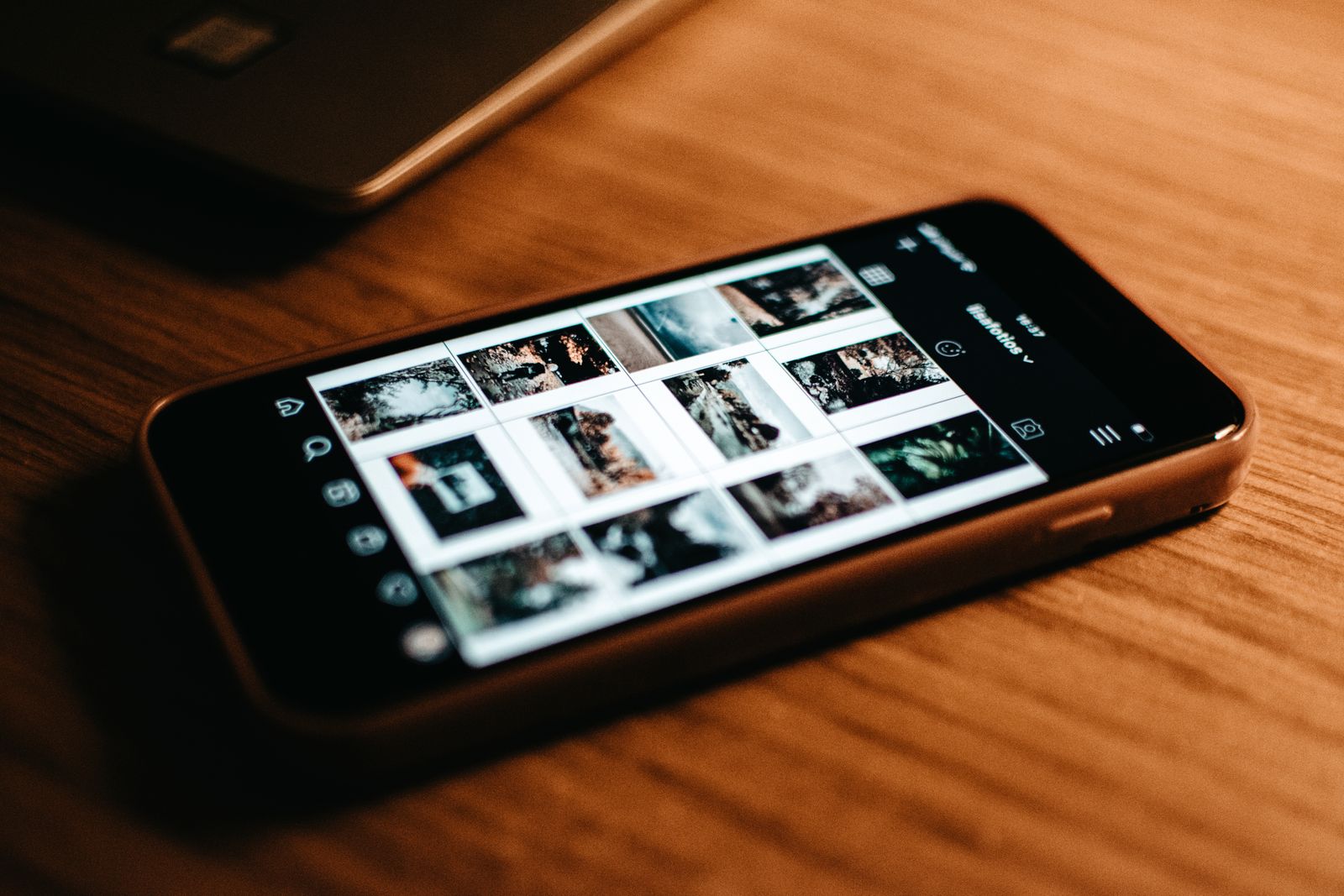 A phone resting on a desk showing a grid of photos — a whole photo library that lives in one place